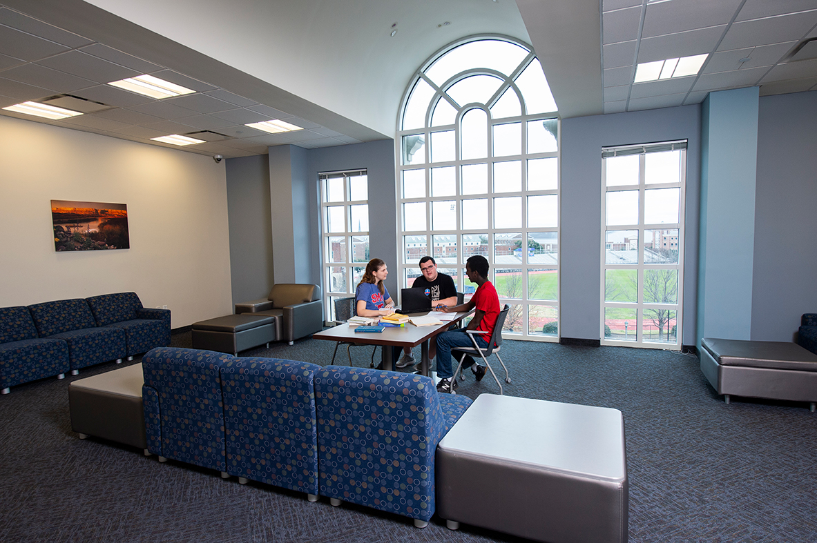 Three students study at a table inside of the Academic Center for Excellence