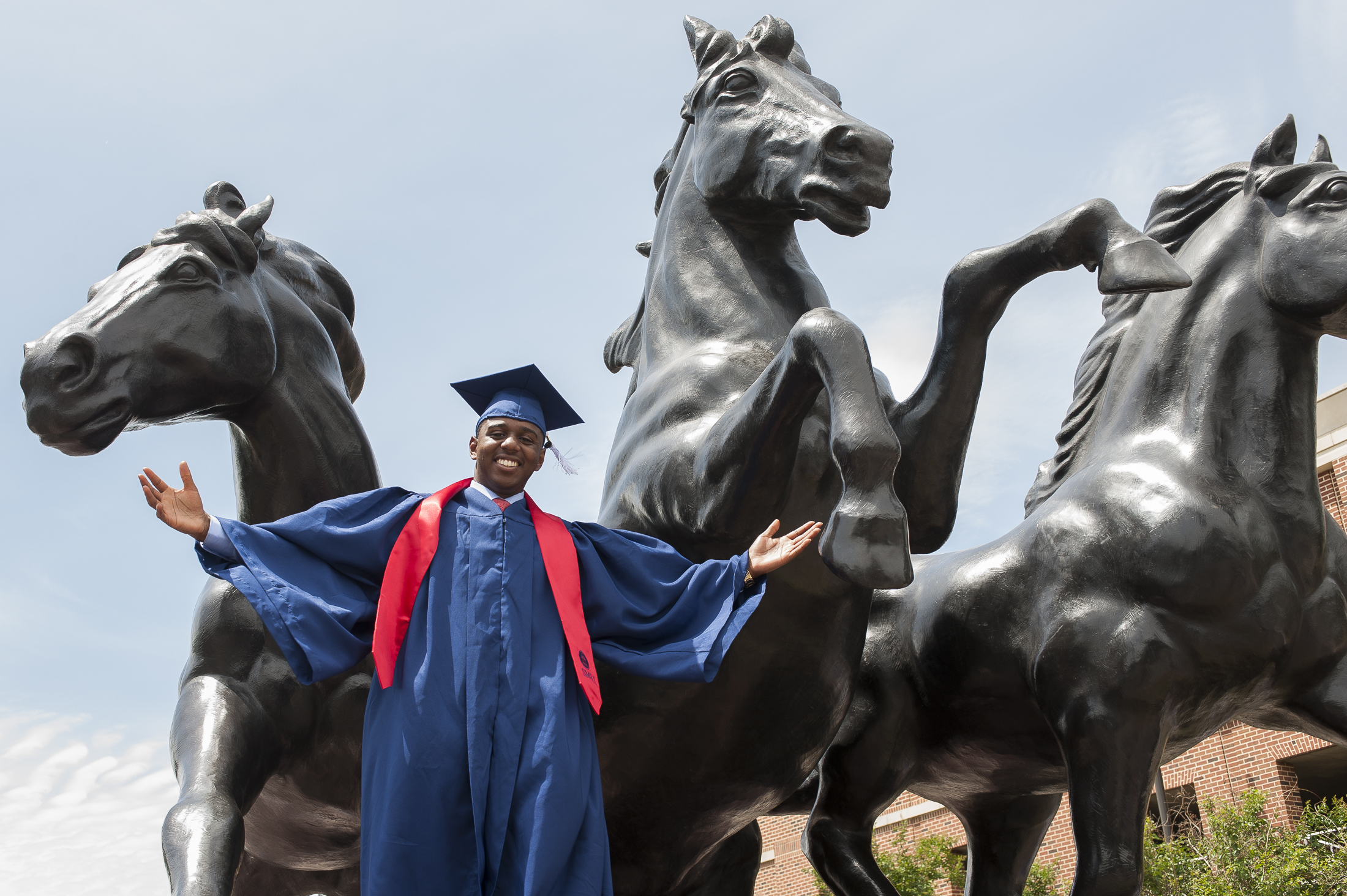 graduate in front of mustang statue