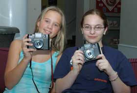 A pair of High school students posing with cameras