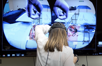 Person in VR headset in front of projected image of surgical simulation