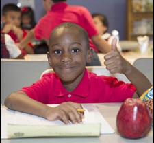 Young child giving a thumbs up gesture in class