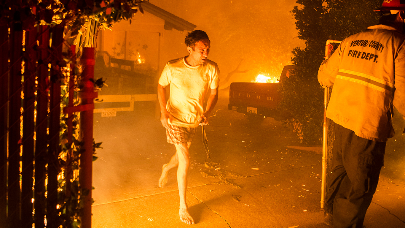 Photo of man running at night while a structure burns.