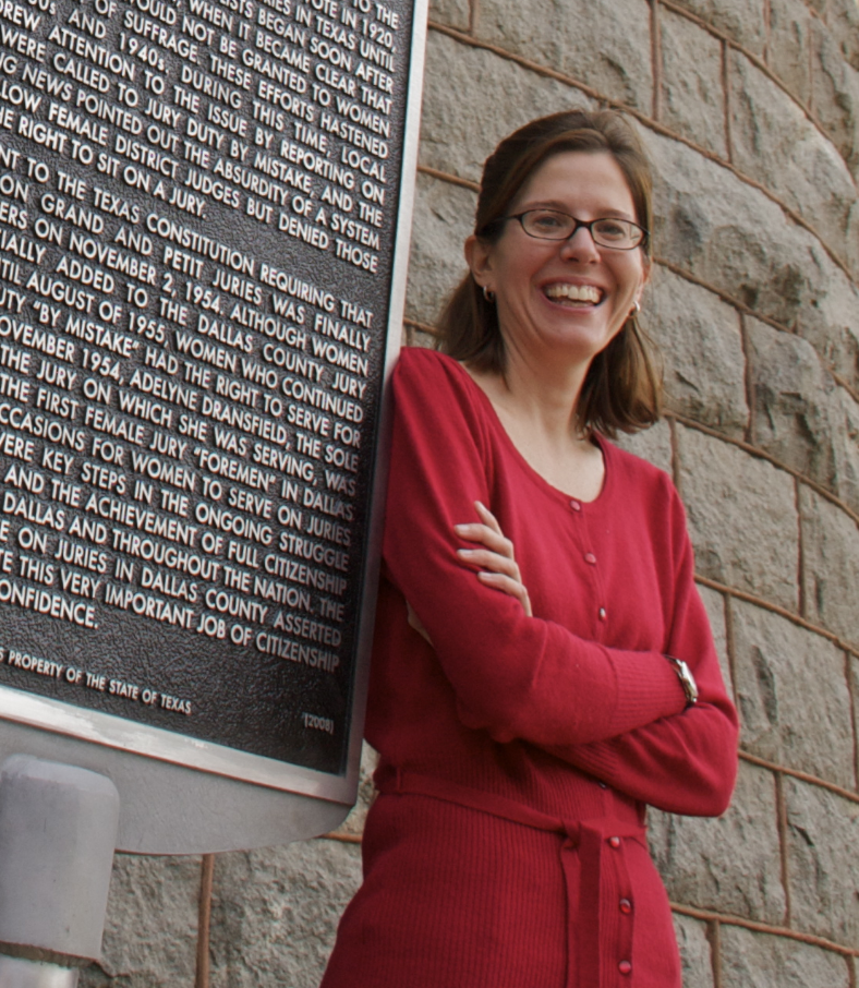 Crista DeLuzio leaning against the historical marker commemorating Dr. Martin Luther King's visit to SMU.