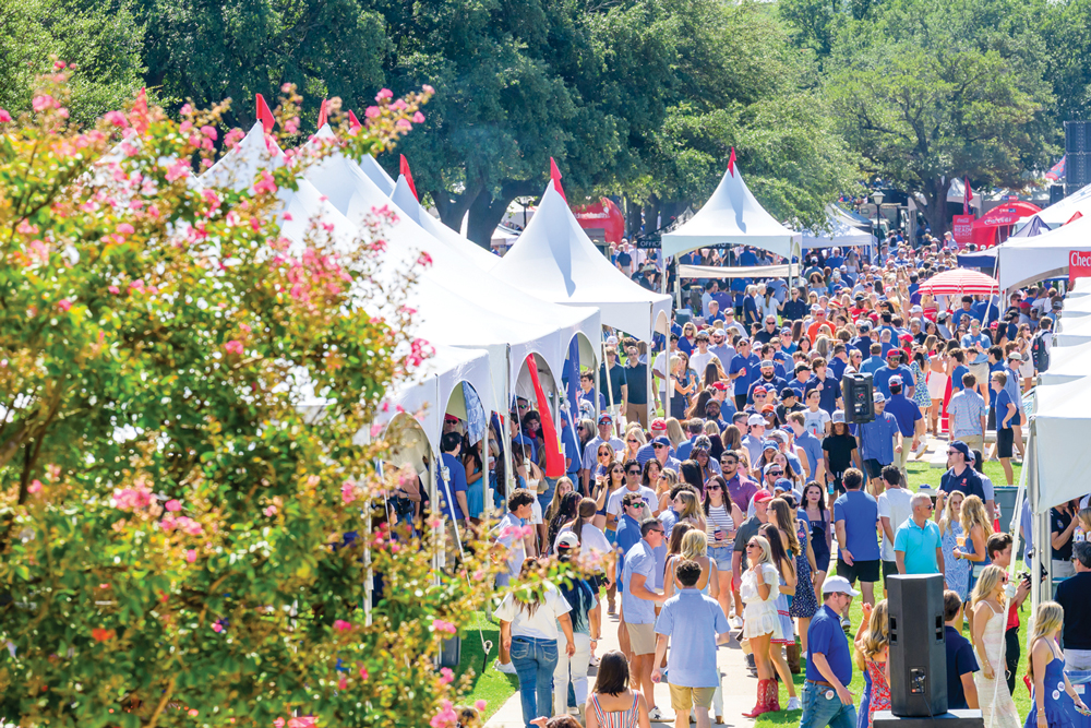 A crowd gathers among white tents on SMU’s tree-lined campus.