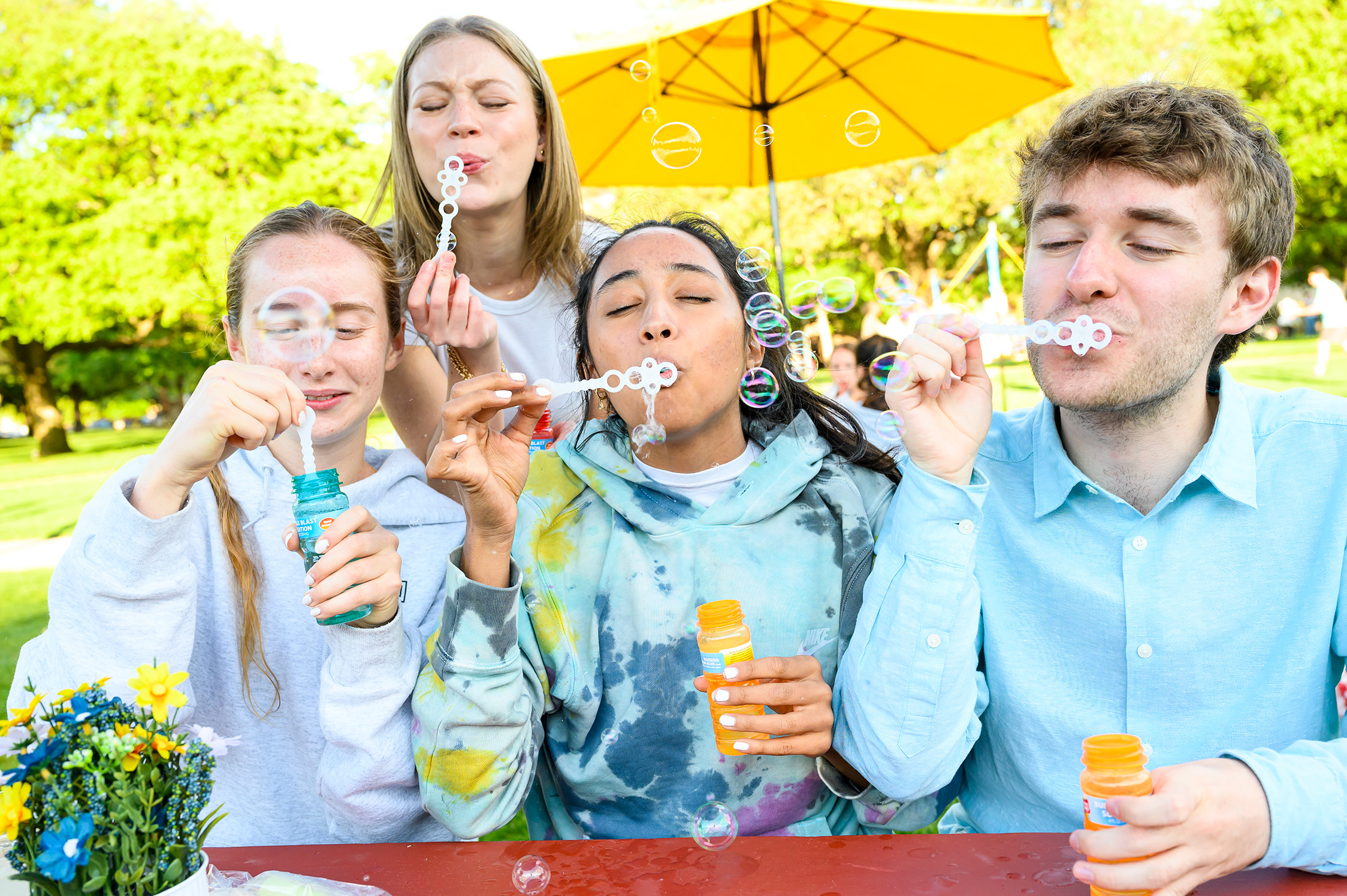 four students blowing bubbles outside