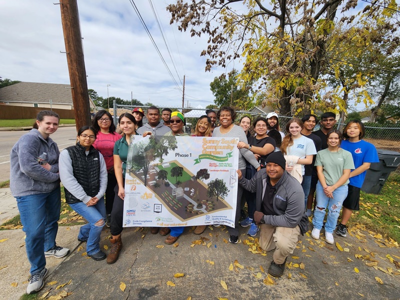 A group of SMU students gather with a sign for the Sunny South Community Garden on an Engage Dallas project