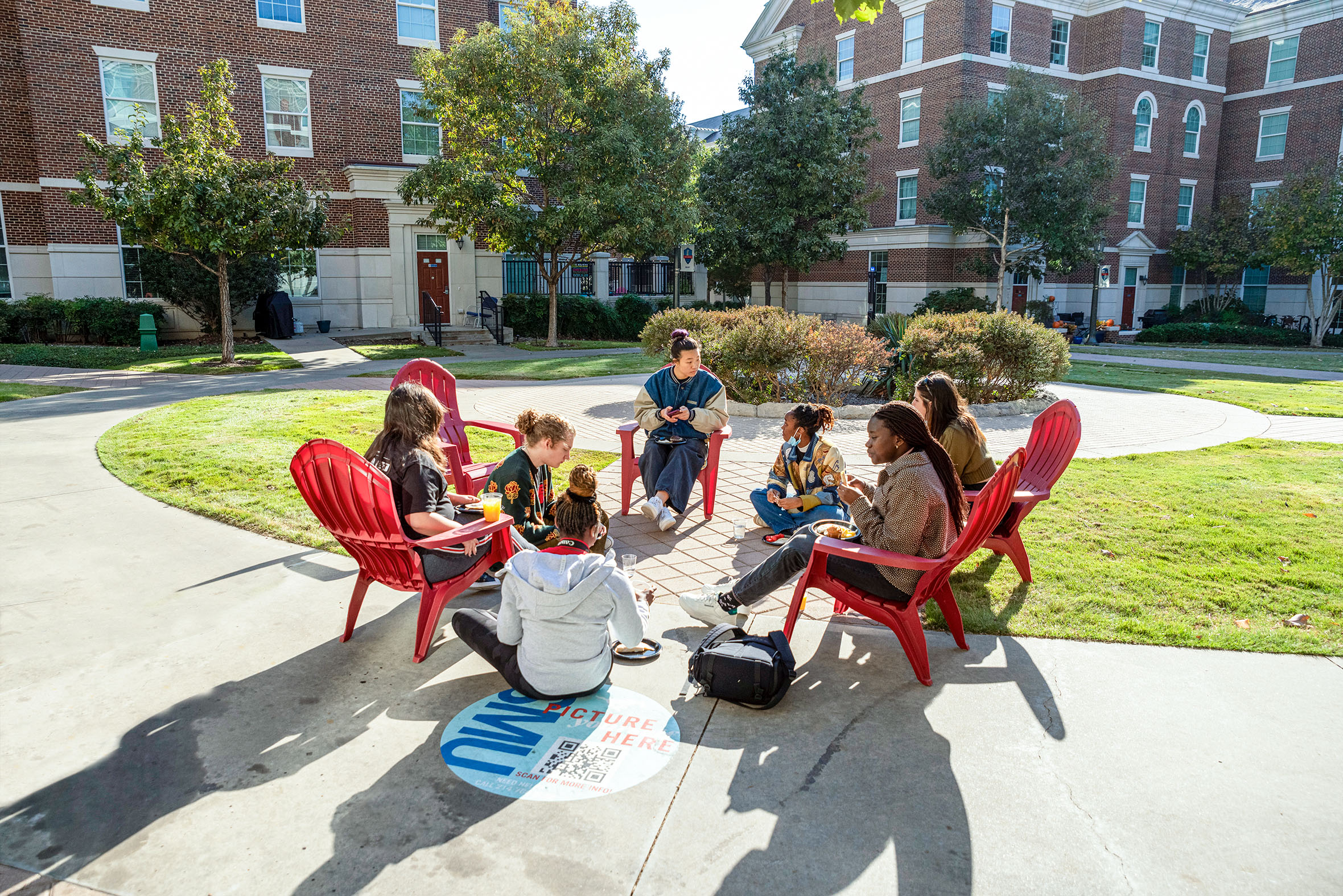 seven students sitting outside in red chairs