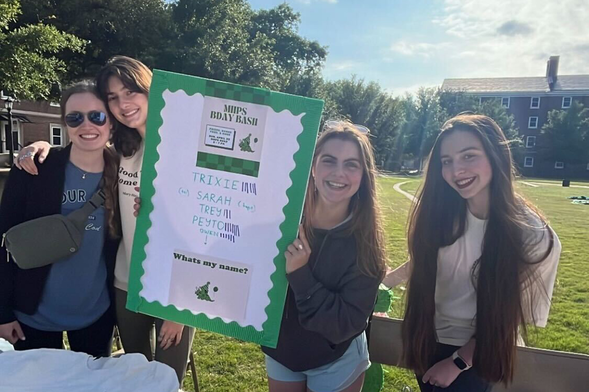 Four students holding green and white poster outside for MHPS Birthday Bash