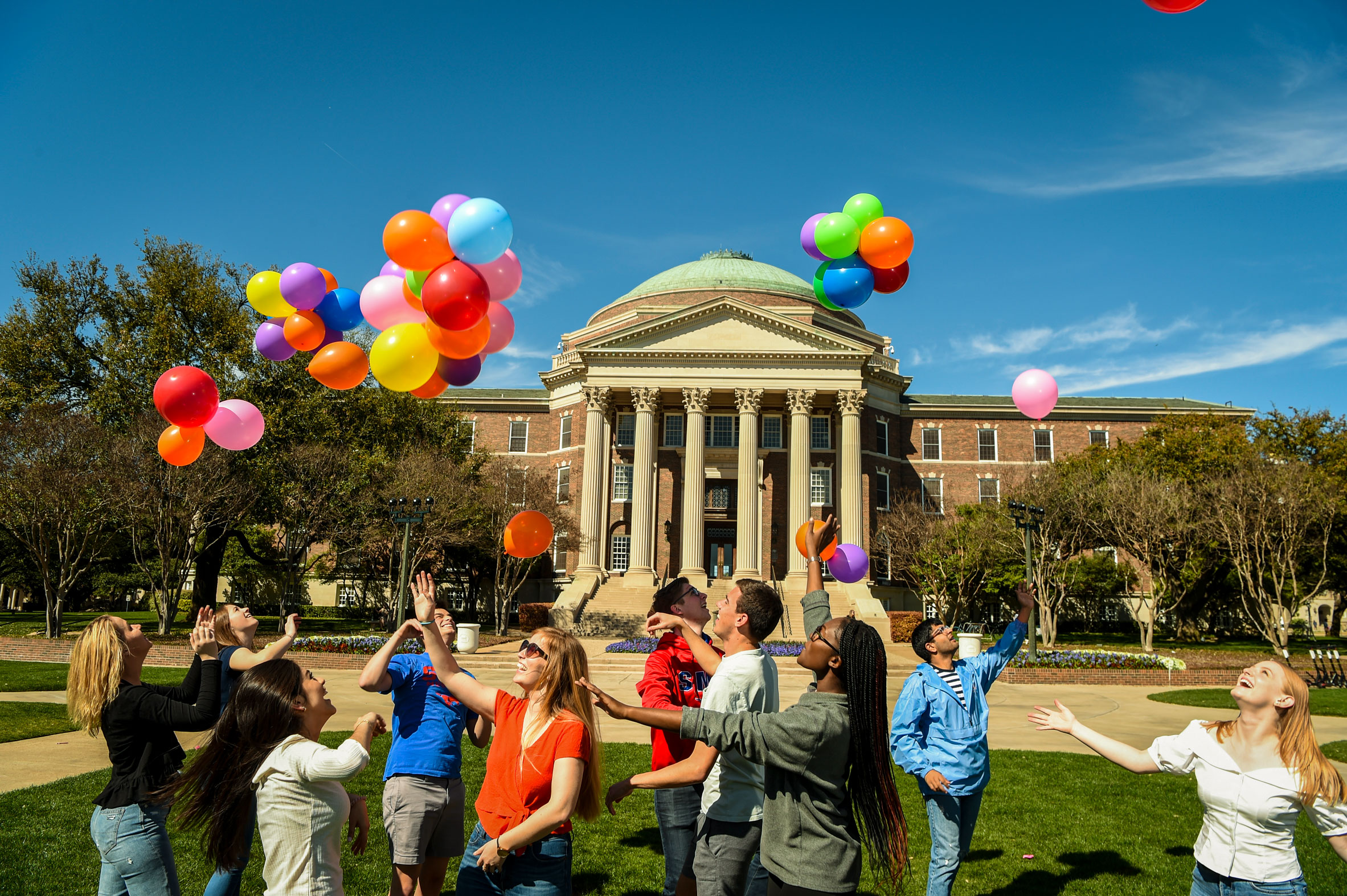 Group of students playing with balloons in front of Dallas Hall.