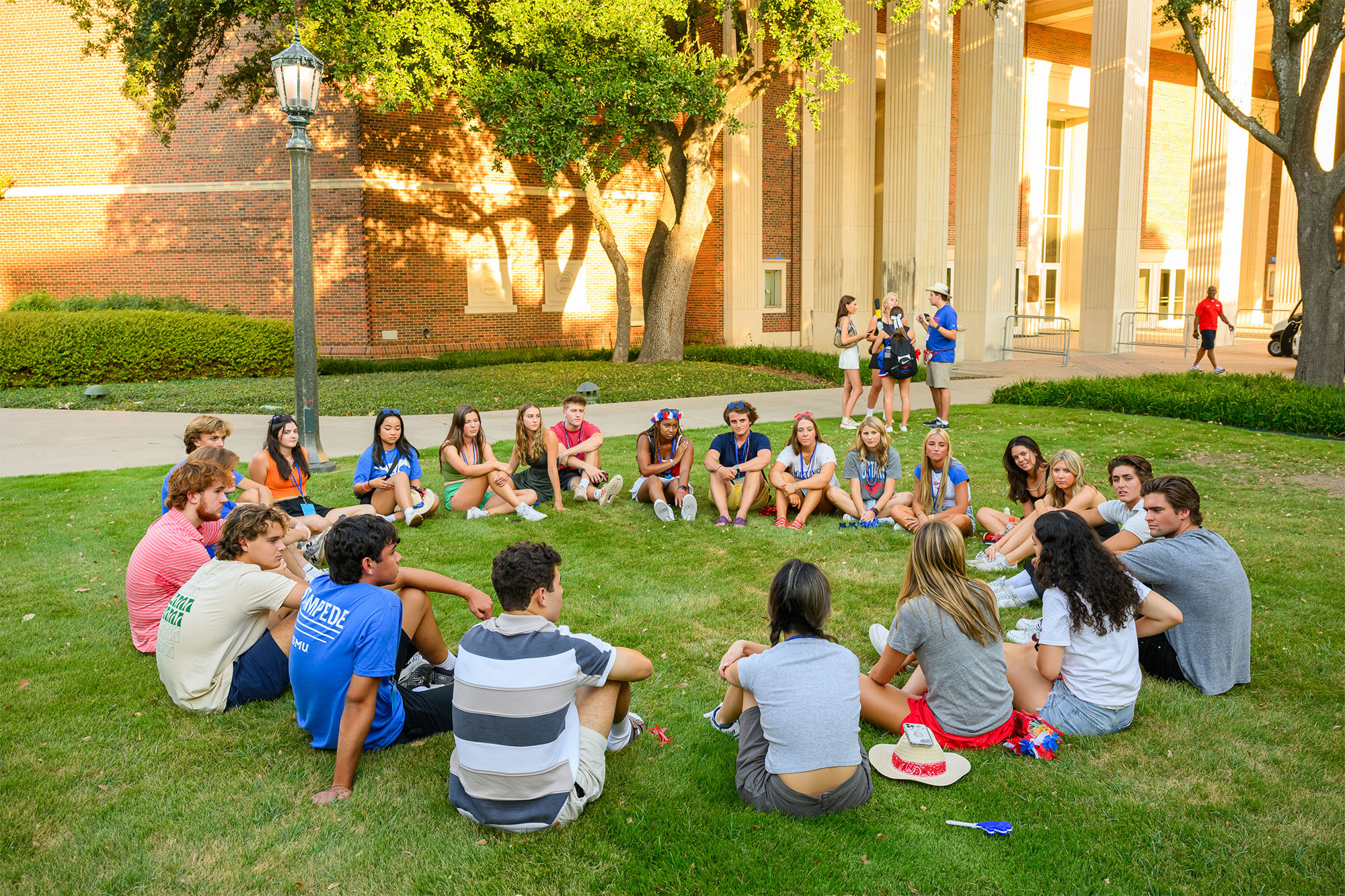 large group of students sitting outside in a circle talking