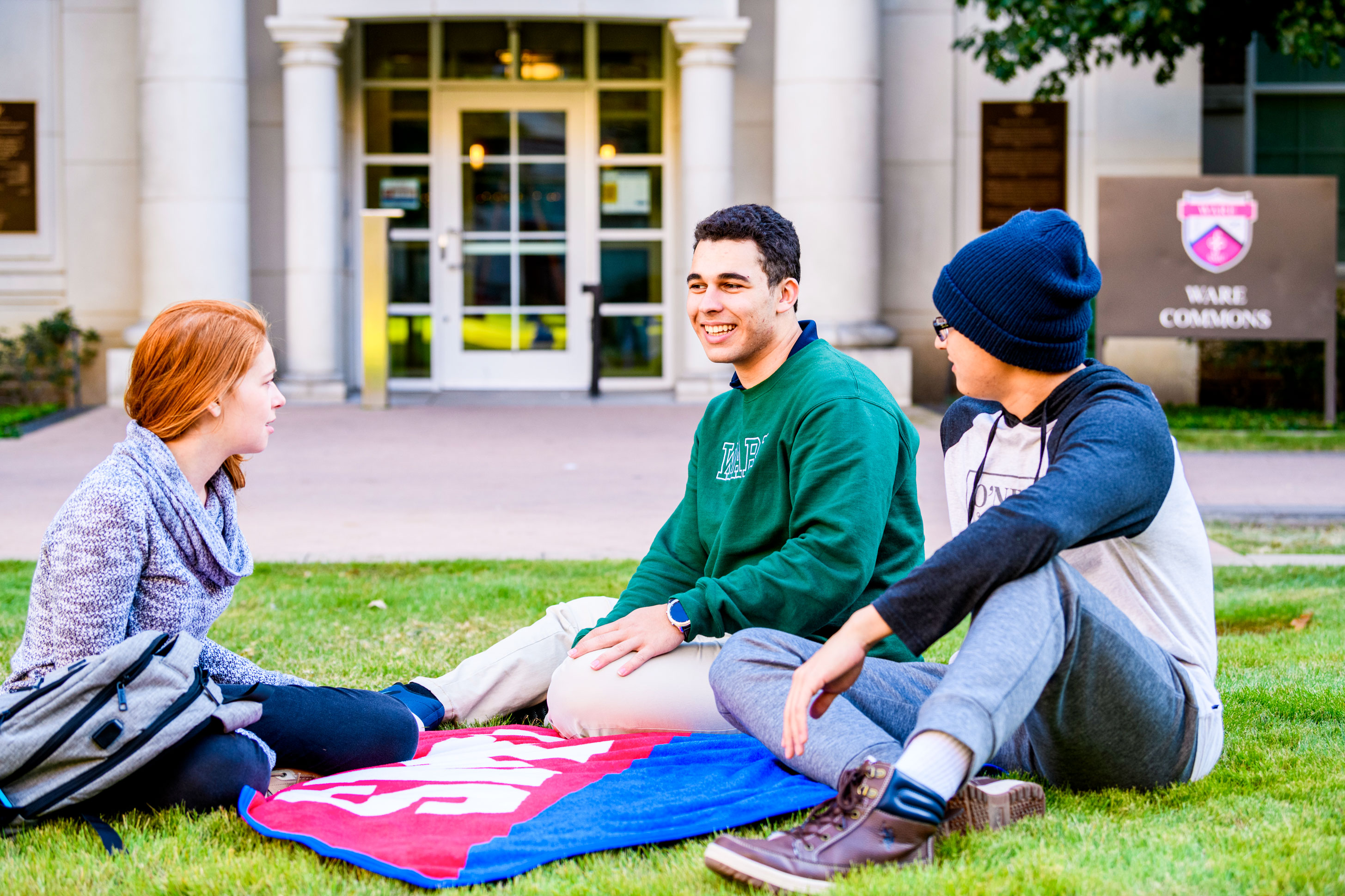 three students talking in front of ware commons
