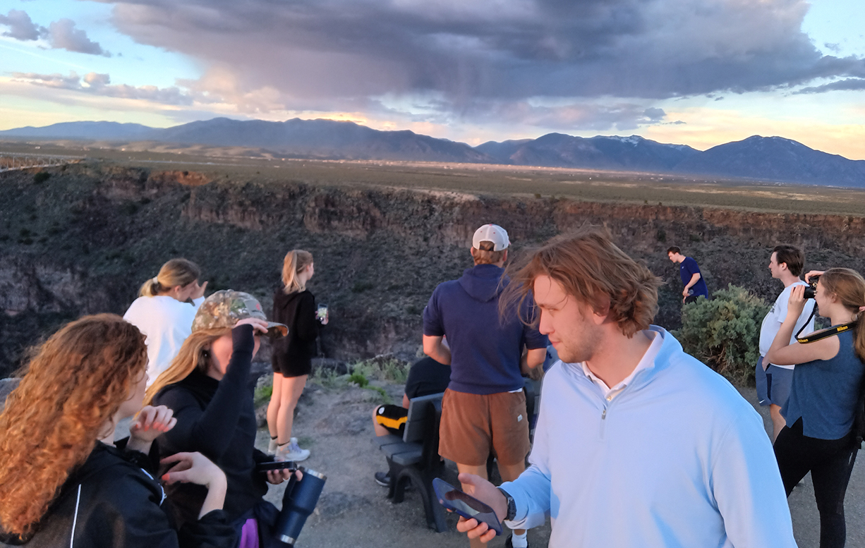 A group of SMU-in-Taos students gather near a bench at the canyon rim.