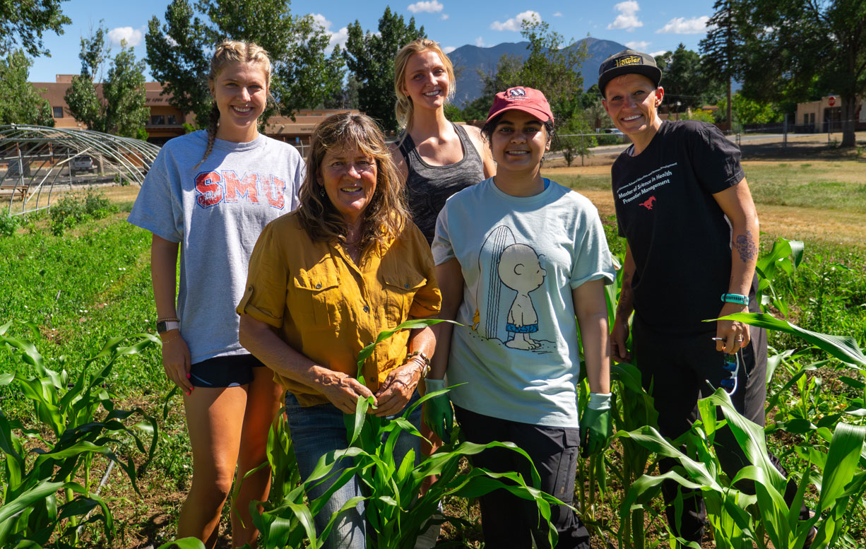 Students and professor standing in group smiling at camera in crops field