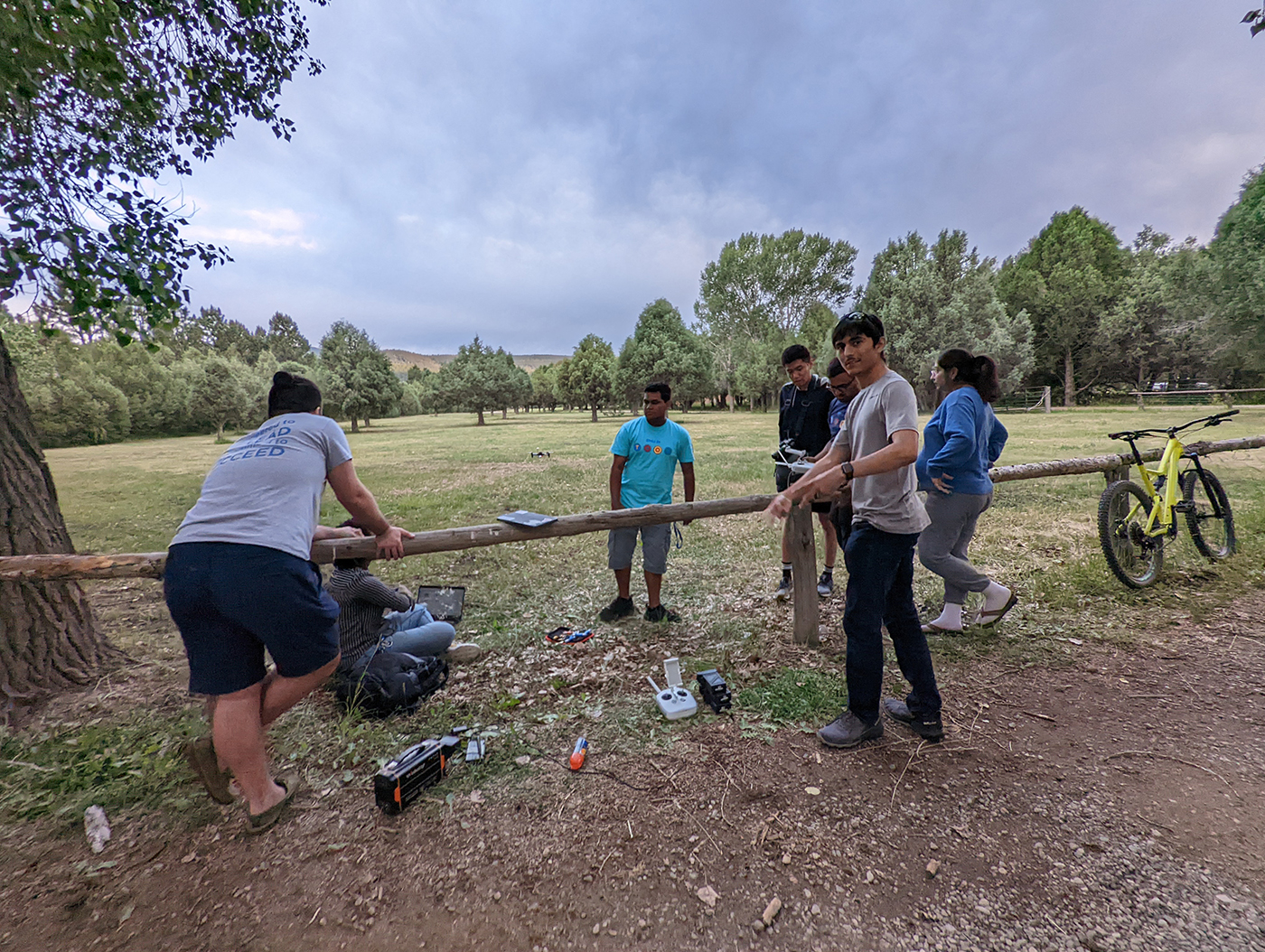 SMU-in-Taos students work with drones near a fence