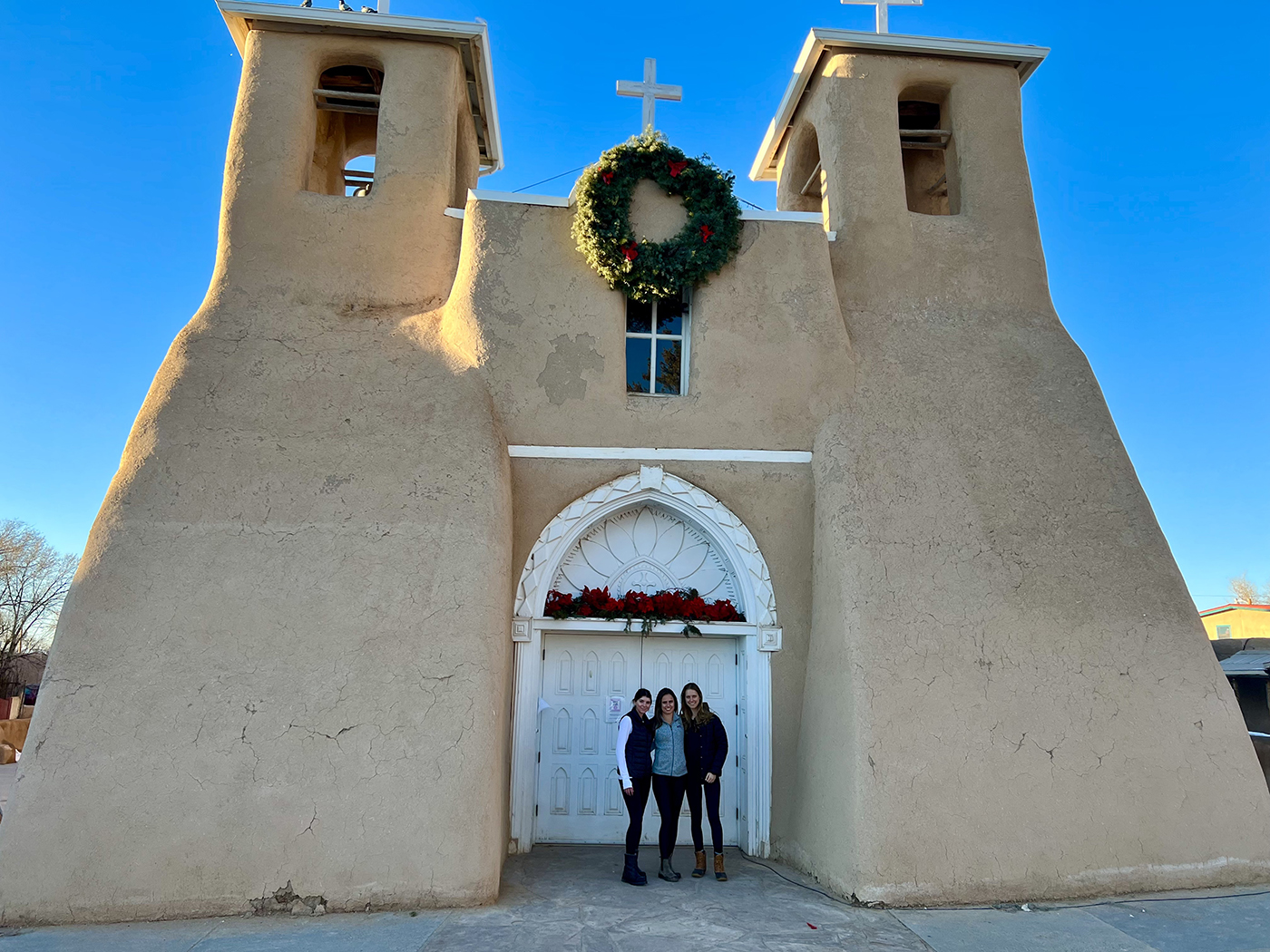 Three SMU-in-Taos students in front of a local church