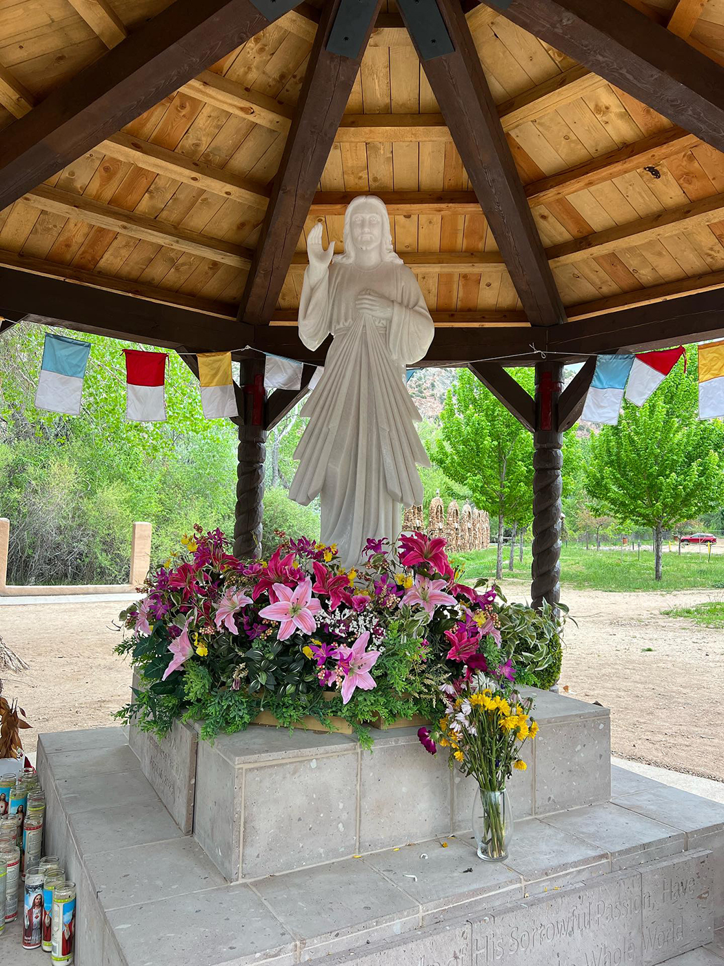 Statue surrounded by flowers and candles in Taos, NM.