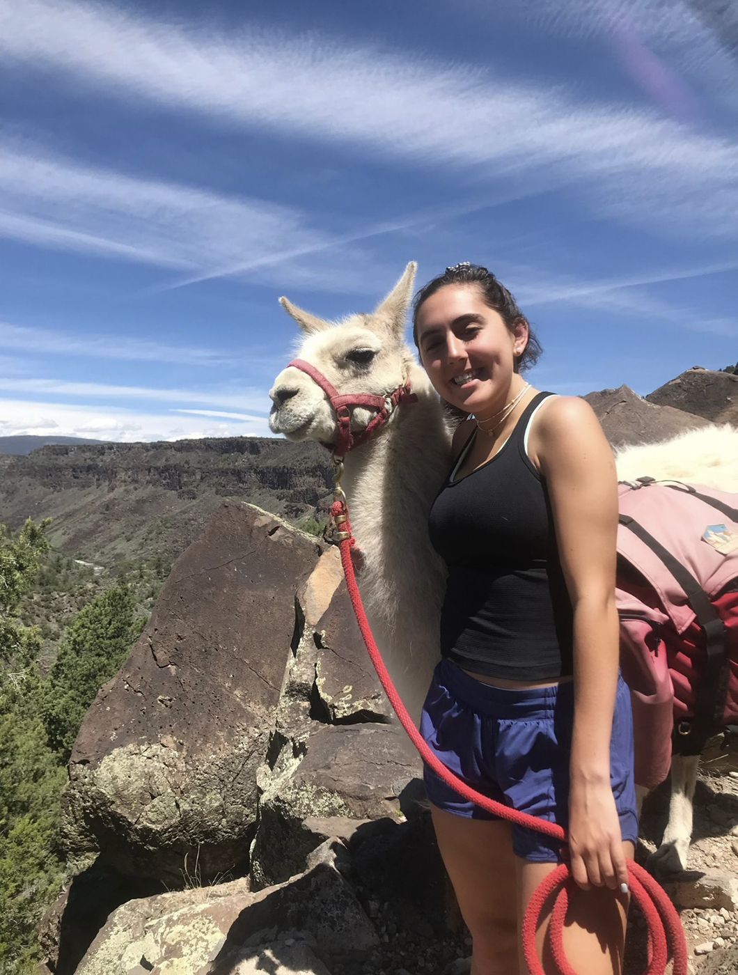 SMU-in-Taos student Aman Sergeant poses with a llama among the rocks in New Mexico