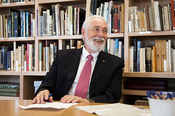 A photo of Richard Duschl, a member of the Lyle School of Engineering faculty, at a table in front of a bookshelf.