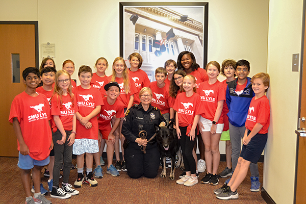 Camp attendees in red shirts pose with campus police officer