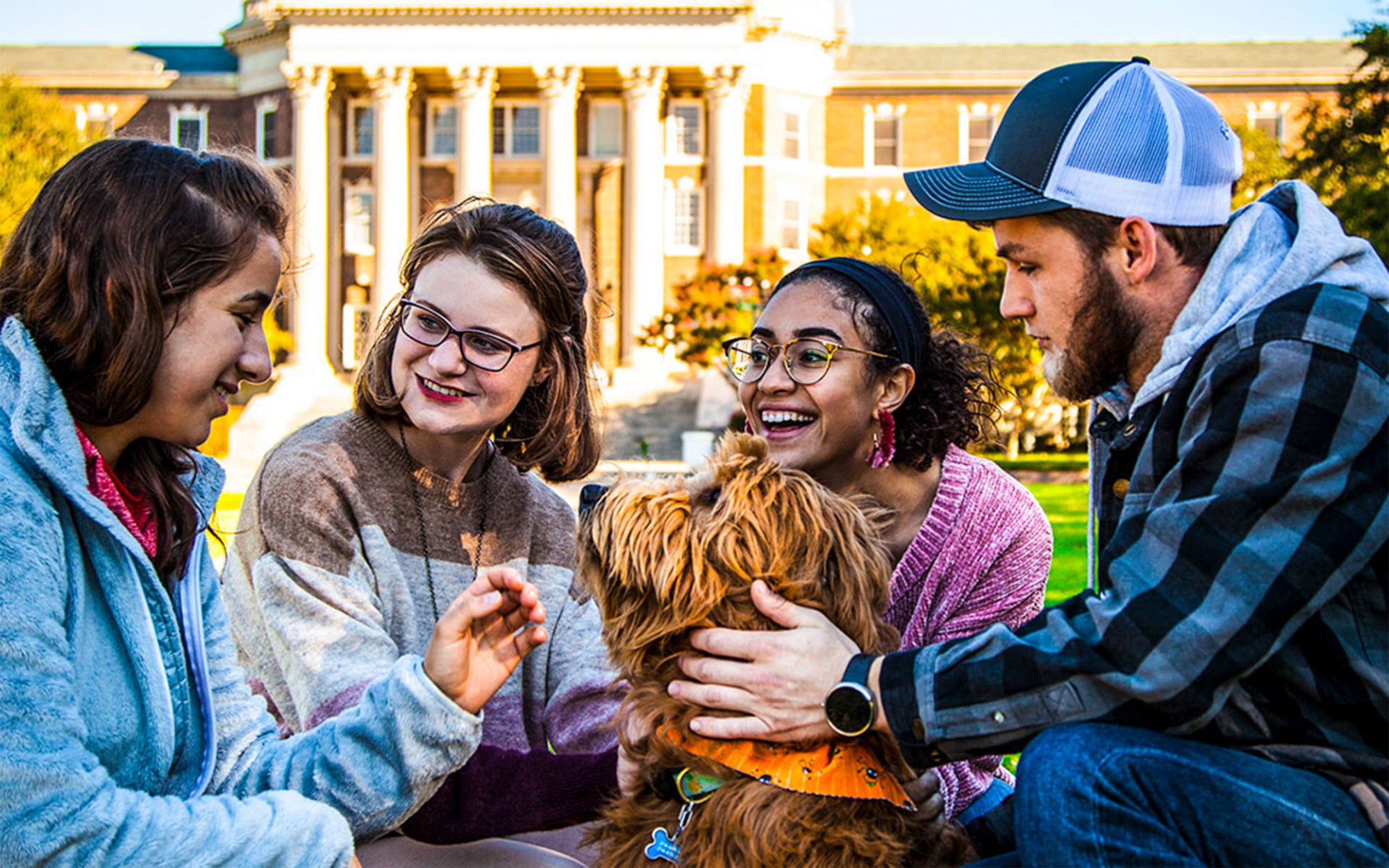Students with dog on the front lawn of Dallas Hall