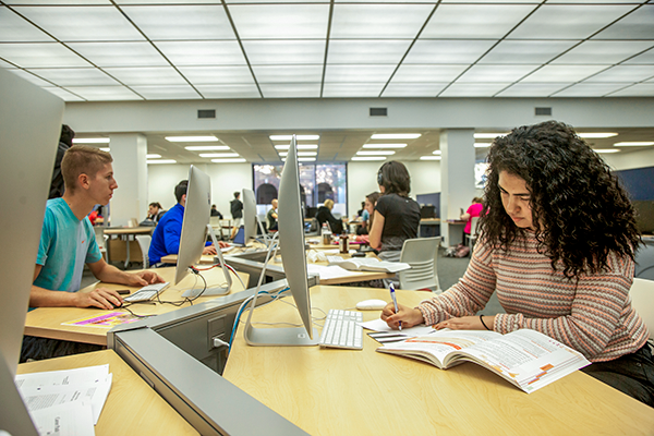 SMU Students working at computers and desks in a library