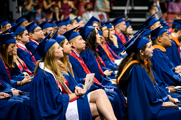SMU students in blue graduation gowns and caps celebrate during a Graduation ceremony.