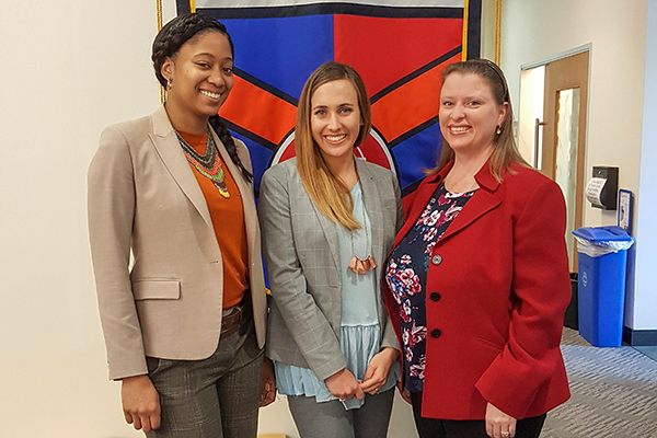 Three smiling women standing together.