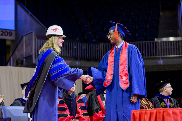 Kathleen Smits shakes a student's hand on graduation day 2024