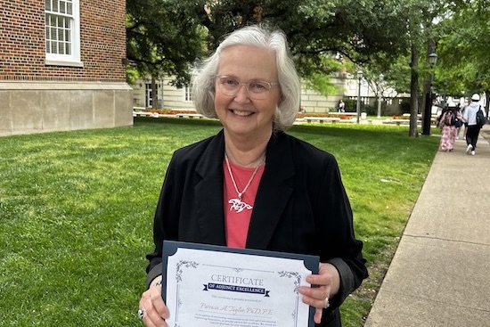 Patty Taylor standing outdoors holding certificate