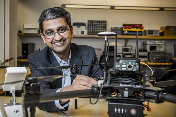 A male faculty member sits behind a drone at a desk