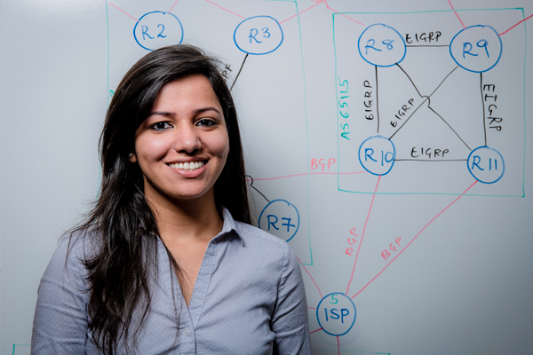 A woman smiles in front of a whiteboard