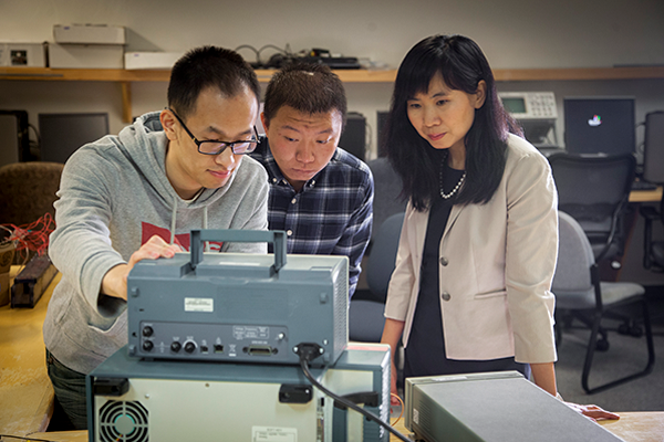 Students gather around a piece of machinery, studying and learning