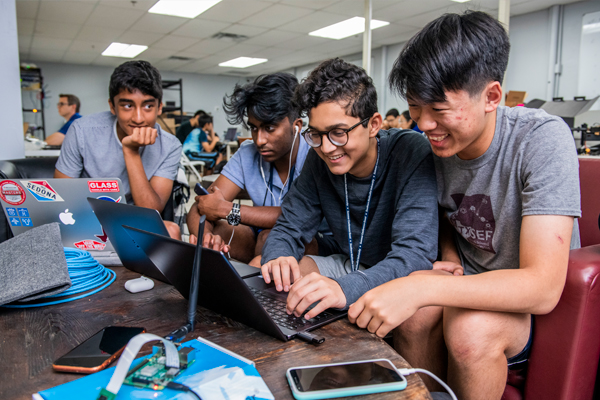 Group of SMU students collaborating on laptops for a computer engineering project.