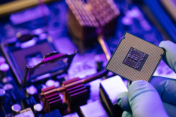 Adobe Stock Image of engineer showing a computer microchip on motherboard background. Electronic circuit board with processor