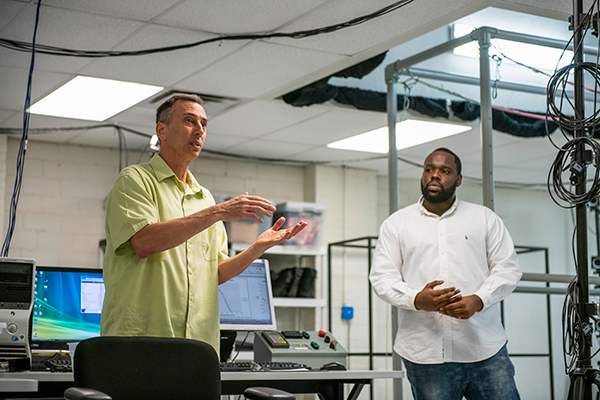 Two researchers working with lab equipment in a technical workspace