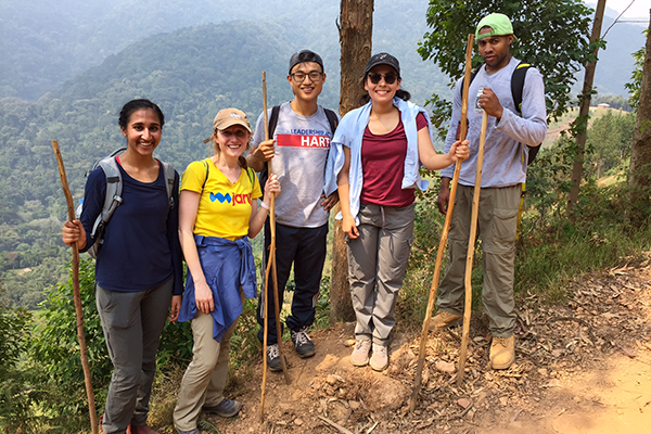 Smu students went to the abord and they are posing with hiking sticks on a mountain trail.