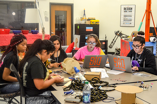 Group of girls  with laptops and robotics equipment in a classroom setting