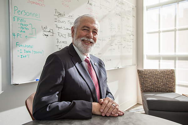 Man smiling at a table in front of a white board