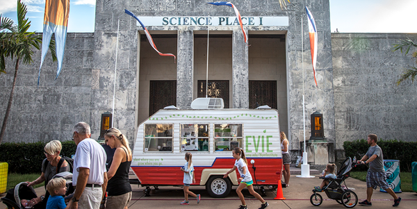 Image of young students working at a desk with iPad, laptop, and radio controller.