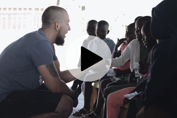 Team member speaking to a group of children in an indoor setting, representing Kijiji Sustainable Solutions.