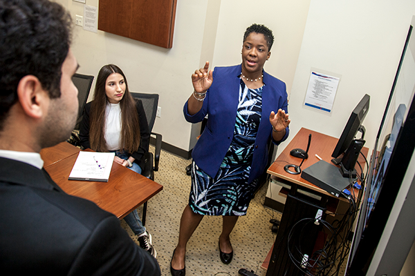 Image: A faculty member speaks in conference room while others look on