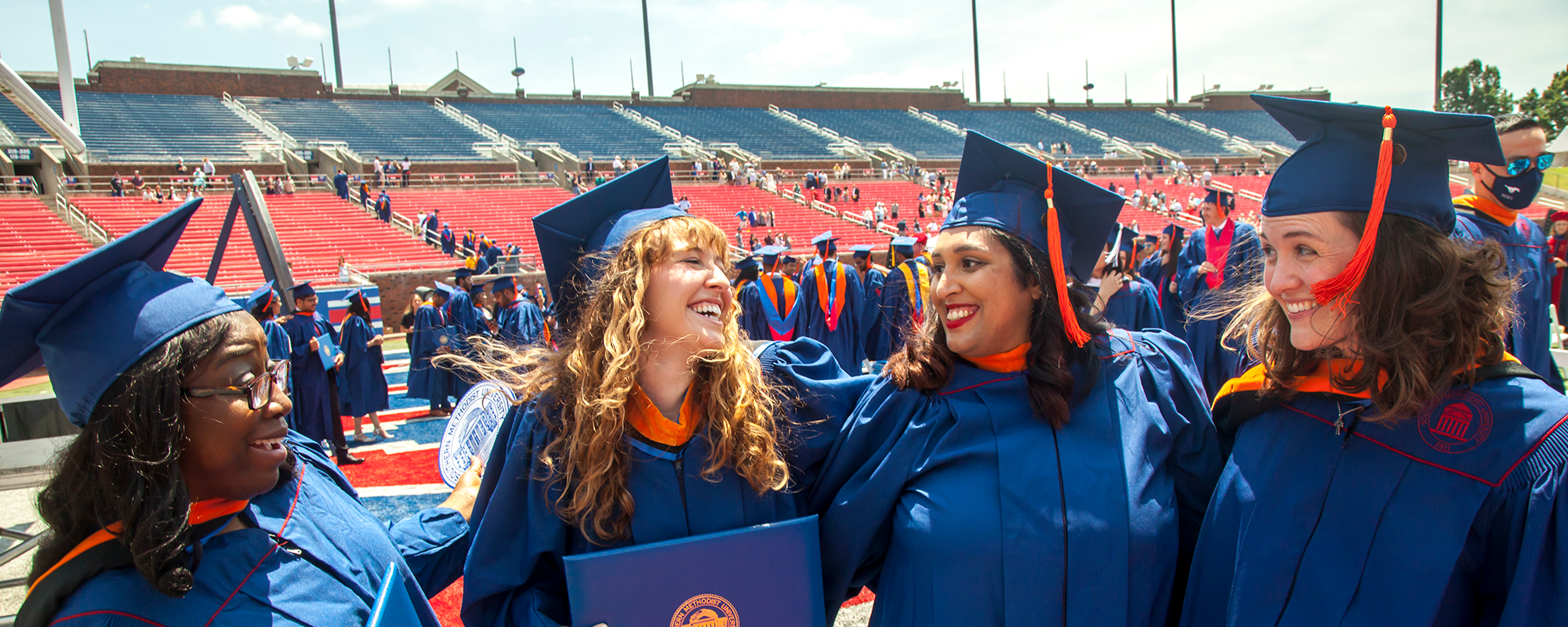 Graduates in blue caps and gowns at an ceremony.