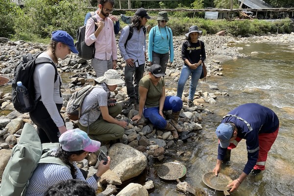 Students observe a man panning a river in Colombia