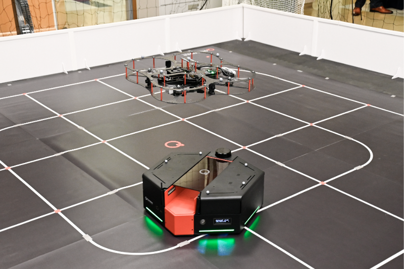 A close up shot of a drone hovering above a small robot in the new SMU Lyle lab.
