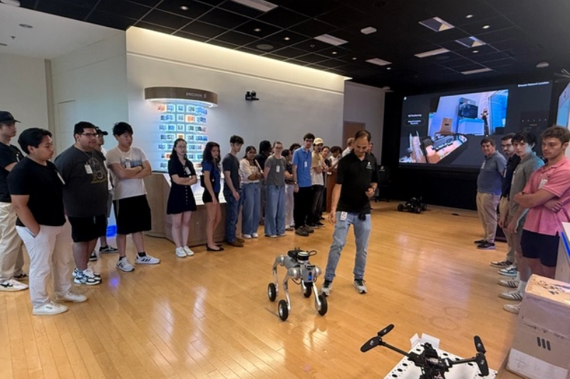 A robotic dog stands in the center of a group of undergraduate students working on a research project.