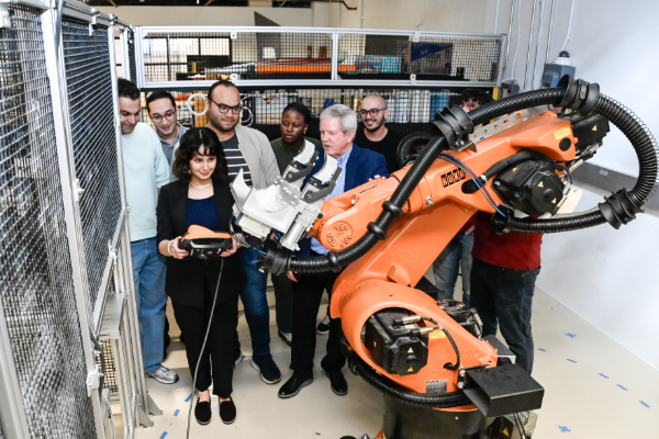 Students stand behind a robot arm in the MS Manufacturing Leadership and Innovation program at SMU Lyle
