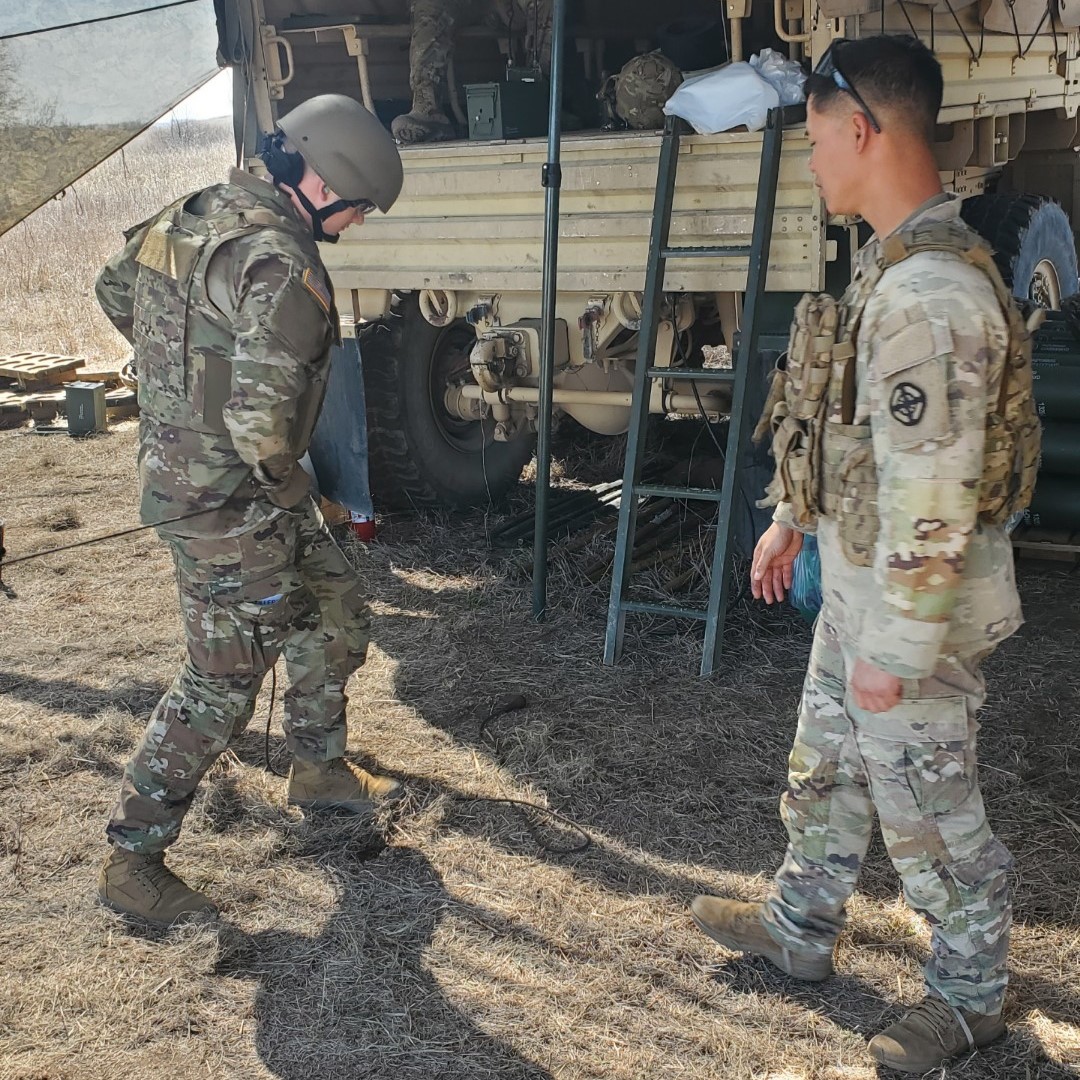 Two people stand beside a military truck