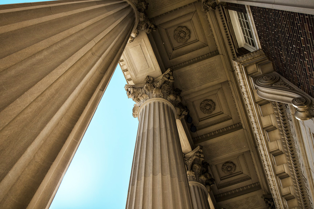 Low-angle photograph of tall neoclassical columns and decorative stonework on a campus building.