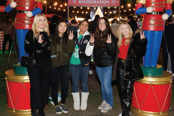 Dallas Hall and the campus trees illuminated with white holiday lights and the fountain glowing in front at night
