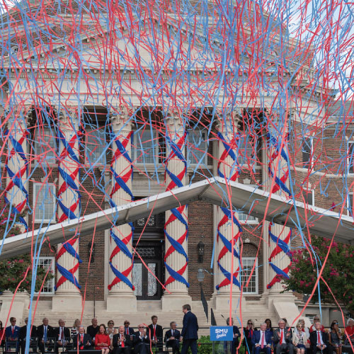 Red and blue streamers cascade in front of Dallas Hall during a campus celebration.